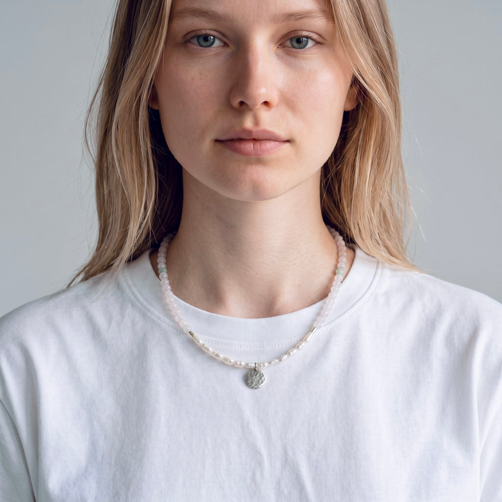 Model wearing the Lunaria sterling silver necklace with white chalcedony, freshwater rice pearls and hammered coin pendant