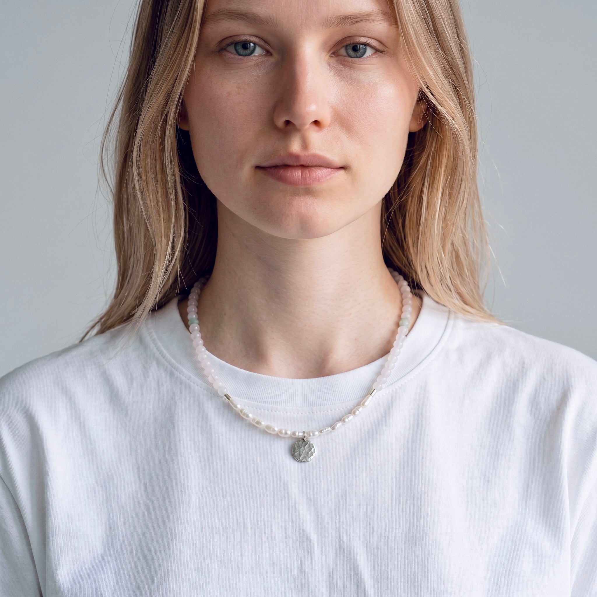 Model wearing the Lunaria sterling silver necklace with white chalcedony, freshwater rice pearls and hammered coin pendant