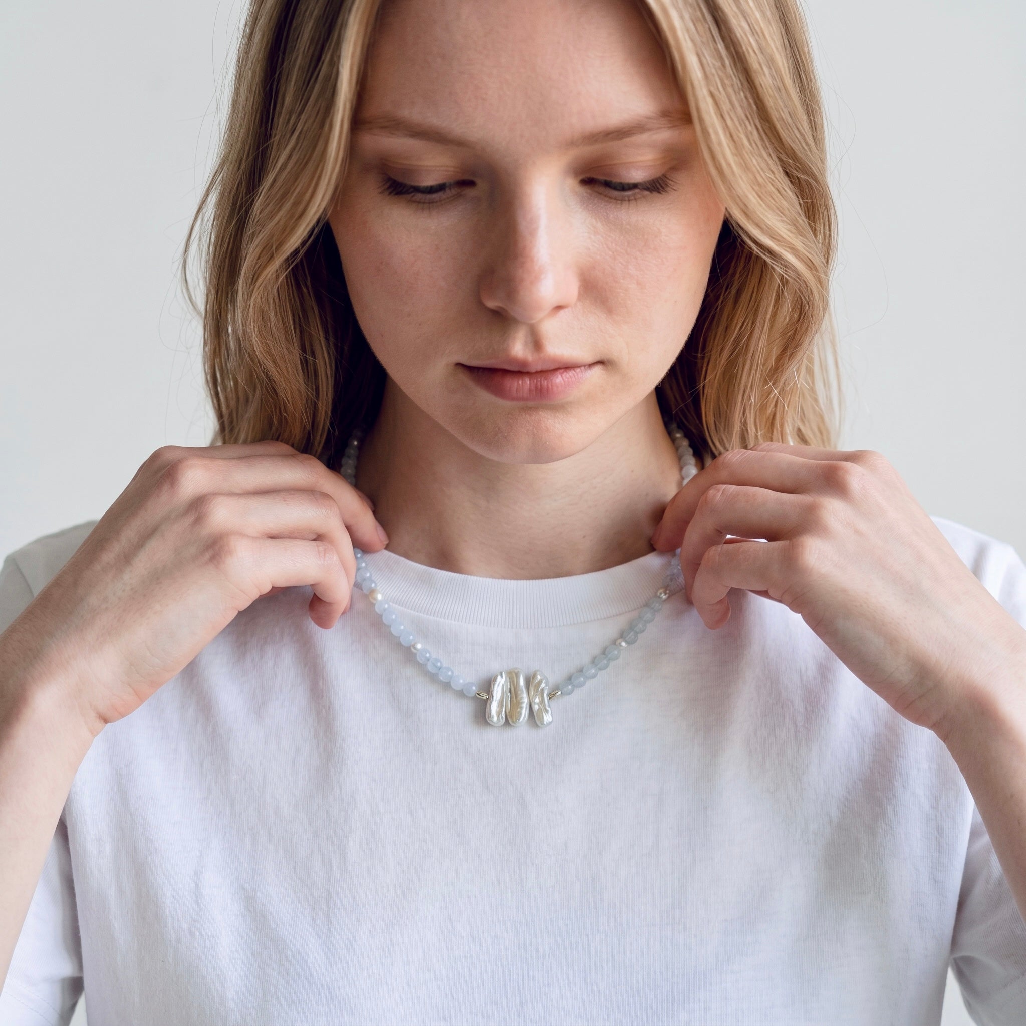 Close-up of model wearing the Nerida white chalcedony and baroque freshwater pearl sterling silver necklace